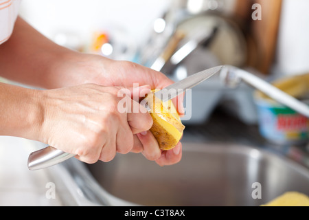 Weibes Hände Closeup, Kartoffelschälen in der Küche Stockfoto