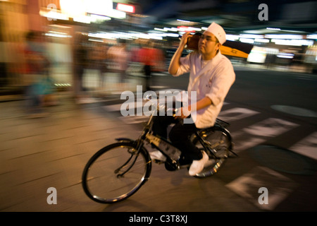 Junge Japaner Fahrrad während des Tragens einer Dichtung auf seiner Schulter, Kyoto, Japan Stockfoto