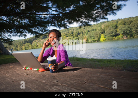 Afrikanische amerikanische Geschäftsfrau sitzt am Picknickbank reden über Handy Stockfoto