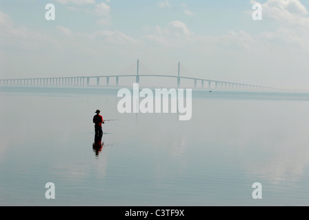 Ein Fischer versucht sein Glück als in der Ferne die Sunshine Skyway Bridge Autofahrer aus St. Petersburg, Florida trägt Stockfoto