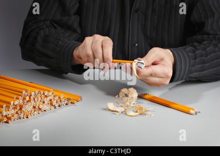 Mann einen Haufen Bleistifte mit einem Bleistiftspitzer schärfen. Stockfoto