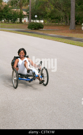 Schwarze Frau, die Spaß beim Fahren der neueste grünen Maschine namens Terre Trike Liegerad Dreirad um unterwegs für Aufregung Stockfoto