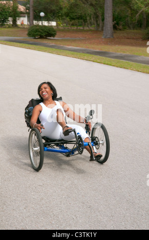 Schwarze Frau, die Spaß beim Fahren der neueste grünen Maschine namens Terre Trike Liegerad Dreirad um unterwegs für Aufregung Stockfoto