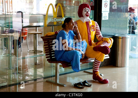 Indische Frau sitzt auf der Bank am McDonalds Fastfood Restaurant, Varanasi, Uttar Pradesh, Indien, Asien Stockfoto