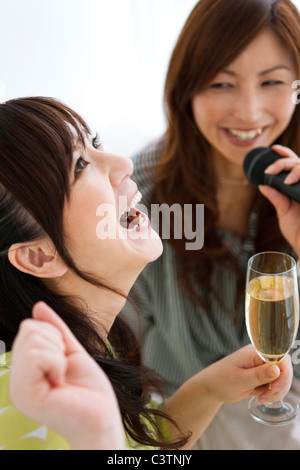 Zwei Frauen Karaoke singen und in Champagner Stockfoto