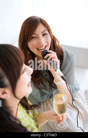 Zwei Frauen Karaoke singen und in Champagner Stockfoto