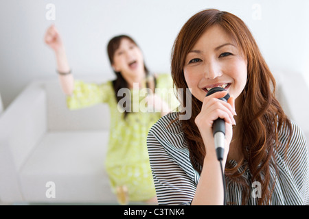 Zwei Frauen Karaoke singen und in Champagner Stockfoto
