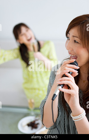 Zwei Frauen Karaoke singen und in Champagner Stockfoto