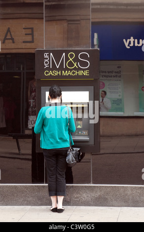 Eine Frau, die immer Geld aus einem M & S Geldautomat ATM, Sidney St, Cambridge UK Stockfoto