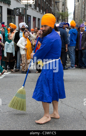 Ein barfuß männlichen Sikh engagiert in eine symbolische fegen der Madison Avenue, bevor die 2011 Sikh Day Parade beginnt Stockfoto