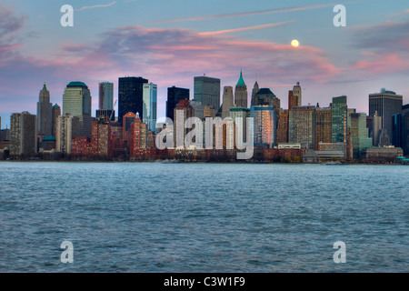 Full Moon rising in lower Manhattan bei Sonnenuntergang über den Hudson River in New Jersey aus gesehen Stockfoto