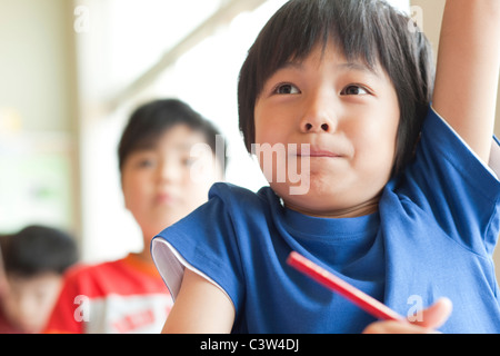 Schüler heben die Hand im Klassenzimmer Stockfoto