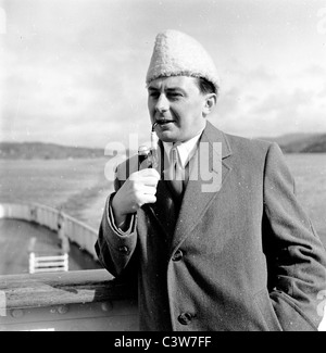 der 1950er Jahre in dieses historische Foto von J Allan Cash sehen wir einen Mann in Mantel und Hut Rauchen ein Rohr auf einer Kreuzfahrt Schiff in Bergen. Stockfoto