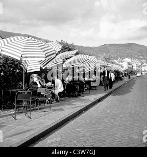 Historische Aufnahme der 1950er Jahre von J. Allan Cash. Menschen entspannen am Straßenrand Tabellen in Funchal, Madeira. Stockfoto