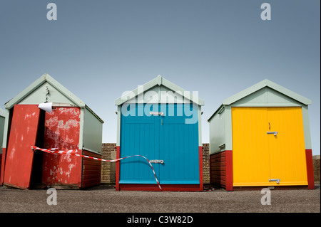 Drei Strandhütten in einer Reihe mit einem sehr heruntergekommen Hütte auf Brighton & Hove, Sussex, England Stockfoto