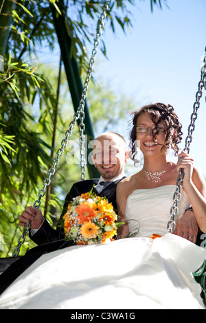 Foto von einem frisch verheiratete Paare, die Spaß auf einer Schaukel im freien Stockfoto