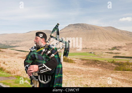 Eine schottische Piper in traditioneller Tracht als Straßenmusikant auf Rannoch Moor in Argyl, Scotland, UK. Stockfoto