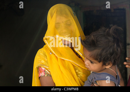 Eine Indianerin gekleidet in traditioneller Kleidung hält ihr Kind in Udaipur, Rajasthan, Indien Stockfoto