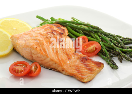 Gesunder Lachs Steak serviert mit gebackenem Spargel, Kirschtomaten und Zitronenscheiben Stockfoto