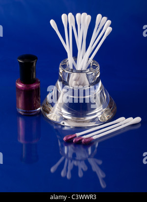 Q-Tipps und Make-up In einem Glashalter auf einem blauen Hintergrund mit einer natürlichen Reflexion Stockfoto
