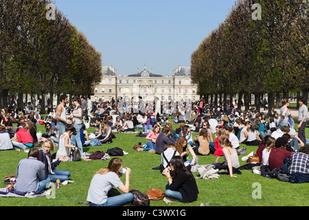 Schüler mit Mittagessen auf dem Rasen vor dem Palais du Luxembourg im frühen Frühlingssonnenschein, Jardin du Luxembourg, Paris, Frankreich Stockfoto