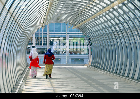 Zurück Blick auf zwei Frauen zusammen entlang Fußgängerbrücke Tunnel gekrümmt abgerundete Form über Bahnlinien Pappel East London England Großbritannien Stockfoto