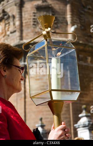 Eine Dame mit einer brennenden Kerze Lampe, die Teilnahme an einer religiösen Prozession ausgehend von der Kathedrale in Sevilla, Spanien Stockfoto