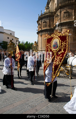 Eine religiöse Prozession, die ausgehend von der Kathedrale in Sevilla, Spanien. Priester tragen Lampen mit Kerzen und Fahnen. Stockfoto