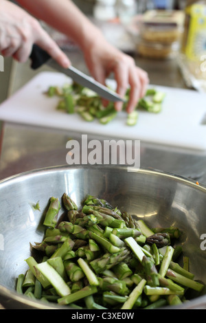 Eine Nahaufnahme von einer Schüssel gehackte Spargel im Vordergrund, mit einer Frauenhand Hacken im Hintergrund. Stockfoto