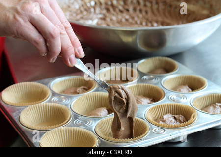 Eine Nahaufnahme von Frauenhand in Cupcake Dosen Teig gießen. Stockfoto