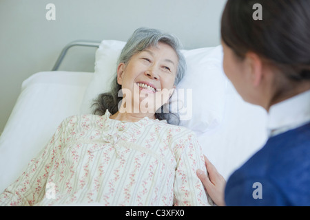 Ältere Frau im Bett lag, im Gespräch mit der Krankenschwester, die Präfektur Kanagawa, Honshu, Japan Stockfoto