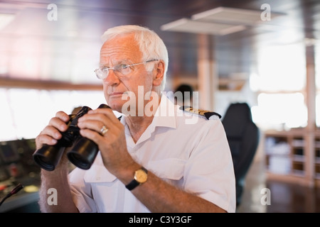 Kapitän auf Schiff hält ein Teleskop Stockfoto
