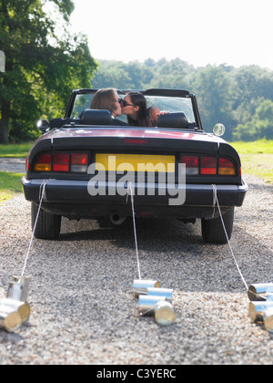 Frisch verheiratetes Paar küssen im Auto Stockfoto