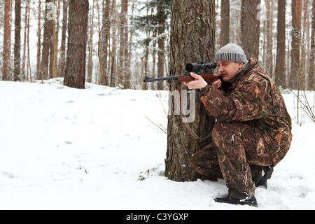 Mann in Tarnung mit Scharfschützengewehr im Winterwald. Stockfoto