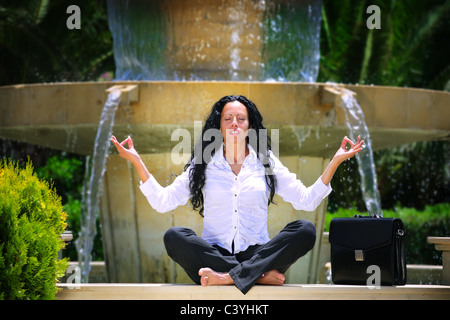 Geschäftsfrau im Freien entspannen, meditieren auf den Rand eines Brunnens. Stockfoto