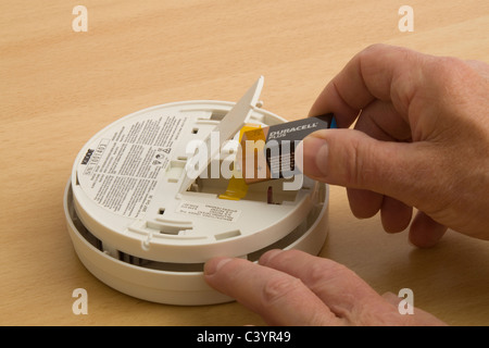 Ein Mann zeigt sich eine Batterie in einen Rauchmelder zu erneuern Stockfoto