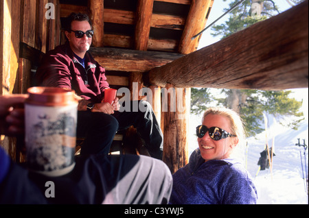 Mann und Frau entspannend auf der Veranda der Skihütte Stockfoto