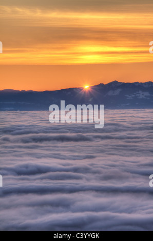 Sonne hinter Vancouver Island mit Nebel über der Straße von Georgia, von Cypress Mountain in West Vancouver aus gesehen Stockfoto