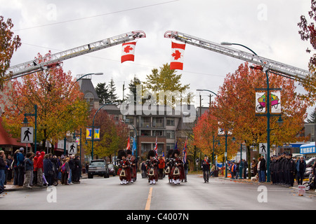 Pipe Band Märsche unter Flaggen aussetzen von Feuer Leitern, 2009 Remembrance Day Parade, Port Coquitlam, BC, Kanada Stockfoto