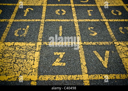 Buchstaben und Zeilen für ein Kinder Spiel gemalt auf dem Asphalt der einen Schulhof - geknackt und peeling. Stockfoto