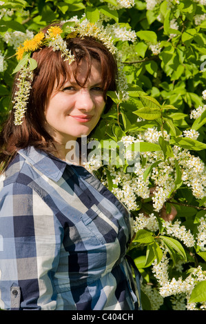 Porträt eines Mädchens tragen einen Kranz auf dem Hintergrund eines blühenden Baumes Stockfoto
