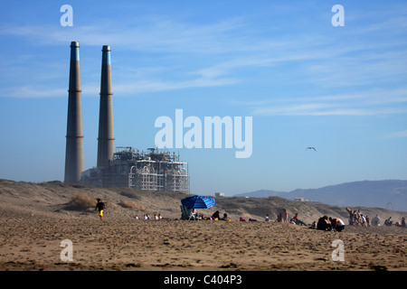 Menschen auf Moss Landing State Beach mit Moss Landing Kraftwerk im Hintergrund Stockfoto