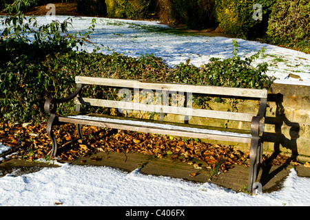 Eine Sitzbank im Schnee an einem hellen sonnigen Wintertag in einem Park Stockfoto
