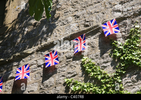 Union Jack Fahnen hängen über einer alten Mauer. Stockfoto