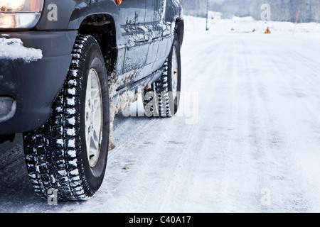 Nahaufnahme von einem Pkw-Reifen auf einer verschneiten Straße Stockfoto