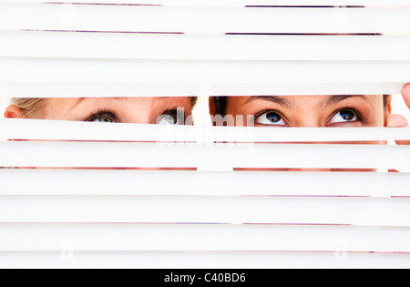 Zwei Frauen schauen Sie durch Jalousien Stockfoto