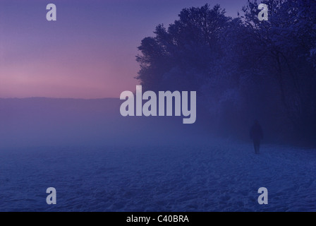 Wandern im Nebel. Mann zu Fuß in der Ferne im Nebel. Feld in der Nähe von Rimes Lane, Tadley, Hampshire, England, Vereinigtes Königreich. Stockfoto