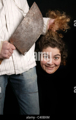 Humorvolle Serienmörder mit großen Messer und abgetrennten Kopf lächelnde junge Frau Stockfoto