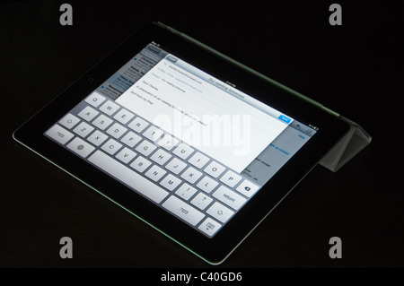 Eine schwarze Wi-Fi-iPad2 mit grauen Smart Cover wird verwendet, um eine E-Mail zu verfassen – das Smart Cover gefaltet ist, um das iPad zu erheben. Stockfoto