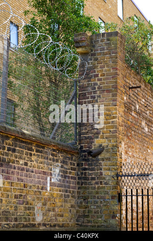 London, Kings Cross, Sicherheitszaun mit Stacheldraht & Spike Eisen Geländer gekrönt mit Sicherheit toped mesh montiert Ziegelmauer Stockfoto